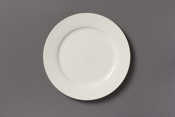 Top view of white empty plate on grey background