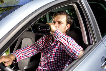Young businesssman drinking alcohol while driving