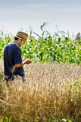 Naklejka na ściany i meble Young farmer standing in a wheat field