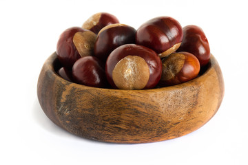 Horse chestnuts in a wooden bowl on a white background