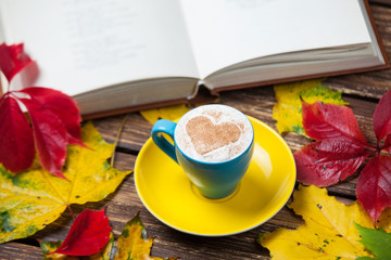 Autumn leafs, book and coffee cup on wooden table.