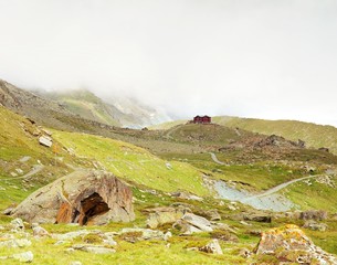 Stony hill bellow snowy Alpine peaks. Sharp Alps mountains