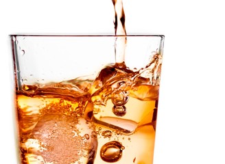 pouring scotch whiskey in glass with ice cubes on white