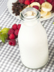 bottle of fresh milk and fuit: banana, raspberries and raisins