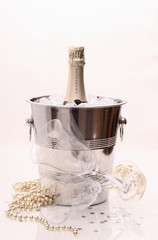 Champagne bottle in cooler and two champagne glasses, deco
