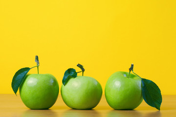 Green fresh apples with leaf against yellow background