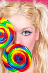 Blonde Frau mit blauen Augen und Lollipops in der Hand