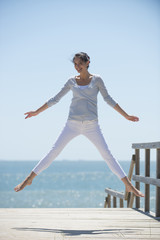 young woman full of energy jumping on a pontoon in front of the