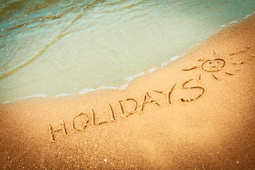 The word holidays written in the sand on a beach
