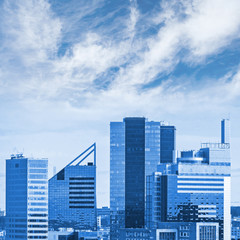 Fototapeta na wymiar Blue cityscape with modern office buildings and cloudy sky