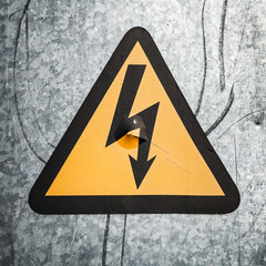 High voltage triangle sign mounted on gray metal wall