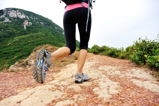 young fitness woman hiker legs walking on seaside mountain trail