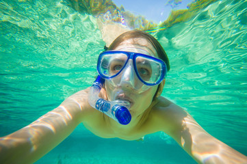 Fototapeta premium Portrait of man snorkeling in crystal clear laguna water on trop