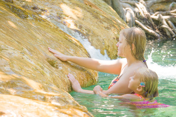 Young mother and daughter swimming in crystal clear laguna near