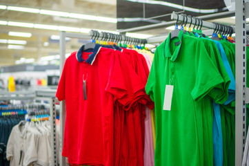 Green and red polo shirts on stand in store