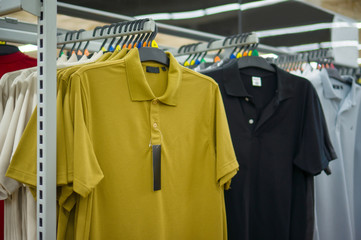 Green and black polo shirts on stand in store