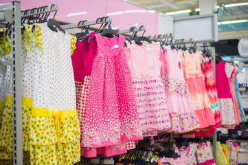 Fototapeta na wymiar Brigth pink kids dresses on stand in store
