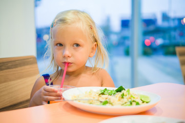 Adorable girl dinning on food court with vegetables rice and jui