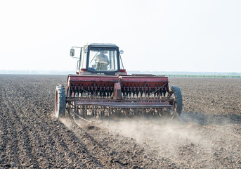tractor and seeder planting crops on a field - 71477595