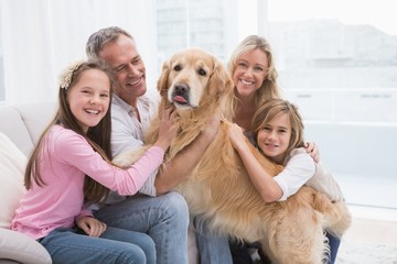 Cute family petting their golden retriever on the couch