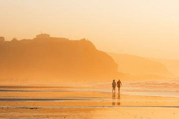 couple walking on beach at sunset
