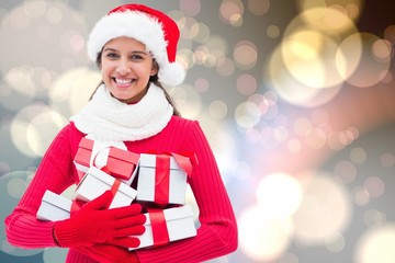 Composite image of festive brunette holding gifts
