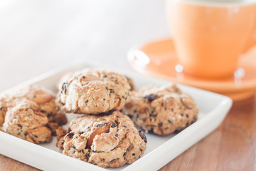 Closeup cereal cookies on white plate with coffee cup