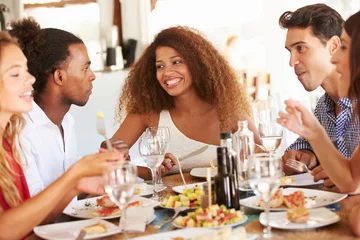 Afwasbaar Fotobehang Restaurant Groep jonge vrienden die van maaltijd in openluchtrestaurant genieten