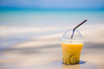 Banana juice shake glass on wet sand on tropical beach