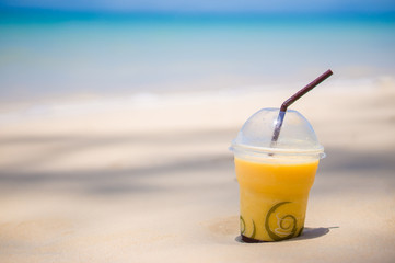 Banana juice shake glass on wet sand on tropical beach