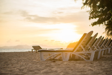 Rows of beach chairs at sunset near tropical ocean resort
