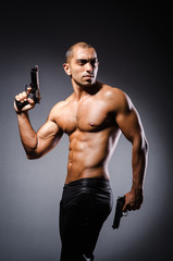 Obraz na płótnie Canvas Ripped man with gun against grey background
