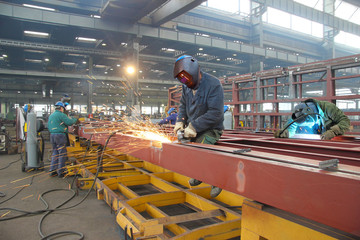 Steel workers welding, grinding, cutting in metal industry