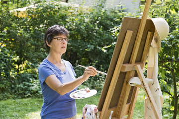 Frau malt ein Bild im Garten