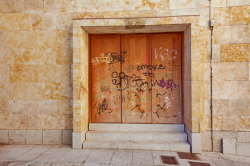 porte en fer rouill&eacute;e sur fa&ccedil;ade de pierre avec graffitis
