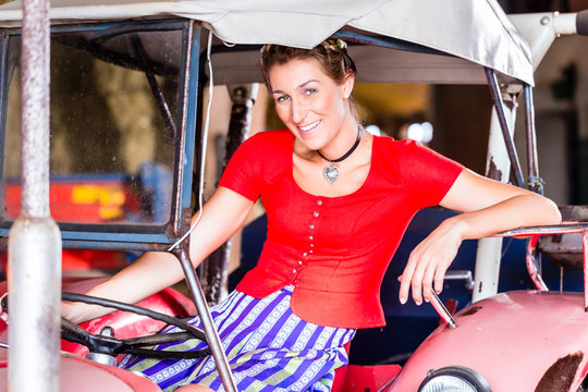 Bayrische Frau mit Dirndl f&auml;hrt Trecker