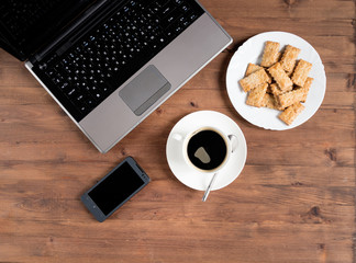 smartphone, laptop, coffee, and a plate of cookies