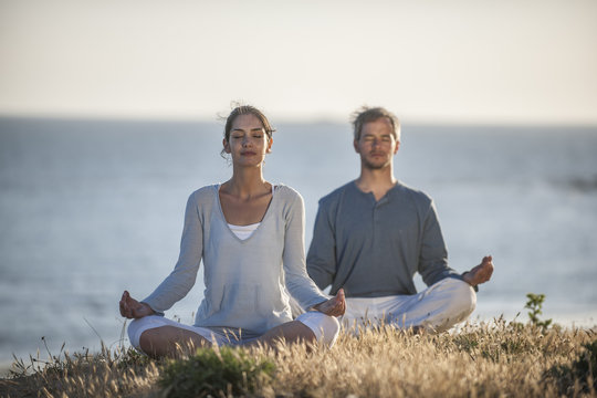 handsome couple practicing meditation exercises on the beach at