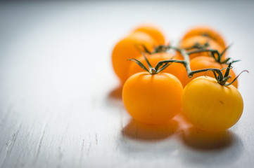 Yellow tomatoes on the vine on wooden background