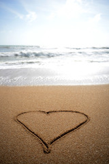 Love heart in the sand at the waters edge.