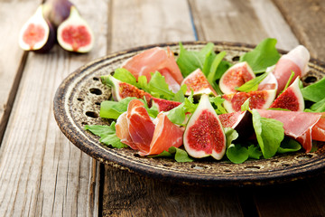 Appetizer consisting of figs, prosciutto ham and rocket salad