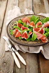 Appetizer consisting of figs, prosciutto ham and rocket salad