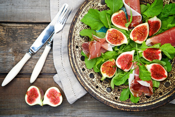 Appetizer consisting of figs, prosciutto ham and rocket salad