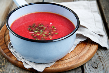 Beet soup in a pot on a wooden background