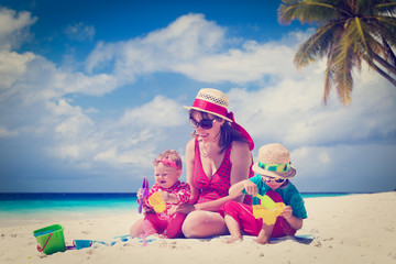 mother and kids playing on sand beach
