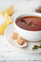 Cup of tasty herbal tea with thyme and lemon on wooden table
