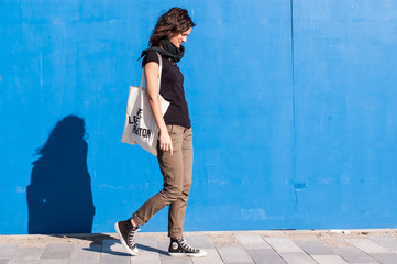 Young girl dressed in brown chinos, sneakers on blue background