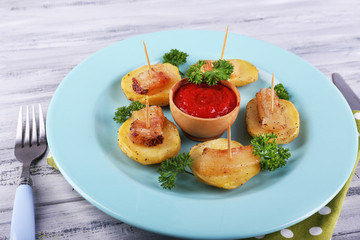 Baked potato with bacon on plate, on wooden background