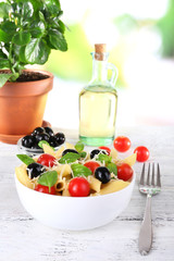 Pasta with tomatoes, olives and basil leaves in bowl