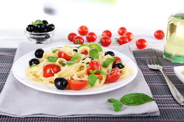 Spaghetti with tomatoes, olives and basil leaves